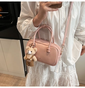 Pink glossy Boston bag detail with bear charm accessory on lace dress model