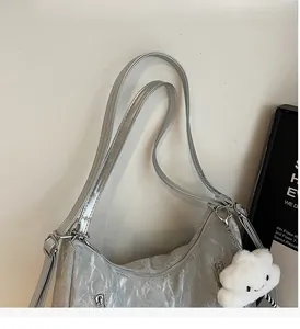 Detail of silver metallic tote bag with pleated texture and white cloud plush pendant