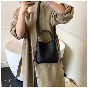 Gros plan sur un sac seau noir en cuir grainé avec poignée et bandoulière amovible