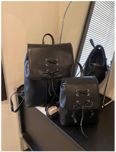Nahaufnahme von zwei schwarzen PU-Leder-Rucksäcken mit Schnürbogen-Design und Metallösen