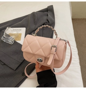 Détail d'un sac à main matelassé rose clair avec fermoir rotatif argenté et bandoulière chaîne
