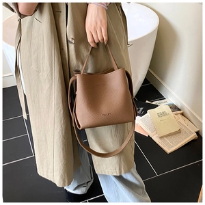 Vue détaillée d'un sac seau en cuir marron avec poignée supérieure et bandoulière réglable