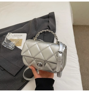 Détail du sac matelassé argenté avec poignée en chaîne et fermoir pivotant
