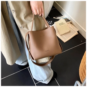 Gros plan sur un sac seau en cuir grainé marron avec poignée supérieure et logo