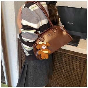 Side view of dark brown wax leather handbag with cute plush puppy charm accessory