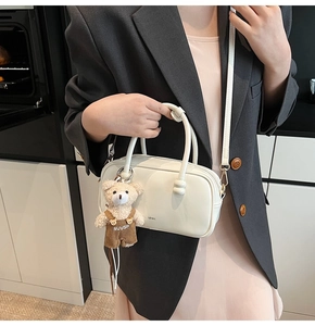 Detail of white patent leather crossbody bag with cute teddy bear charm accessory