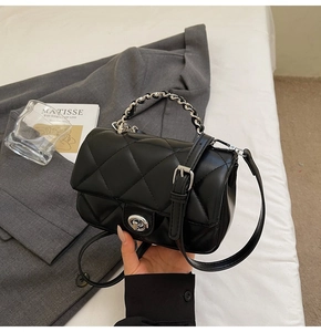 Détail du sac matelassé noir avec poignée en chaîne argentée et fermoir pivotant en métal