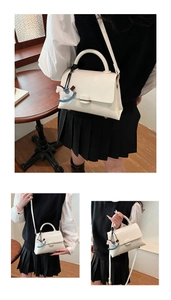 Détail du sac cabas en cuir blanc avec élégant pendentif cheval et bandoulière fine