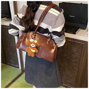 Detail of vintage oil wax leather brown underarm bag with a plush dog charm accessory