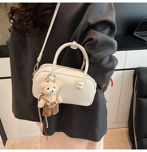 Detail of cream white leather Boston bag with cute teddy bear charm and gold hardware