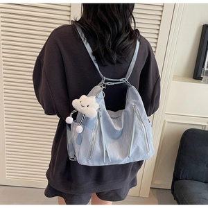 Detail view of light blue versatile backpack with cute cloud charm and silver zippers