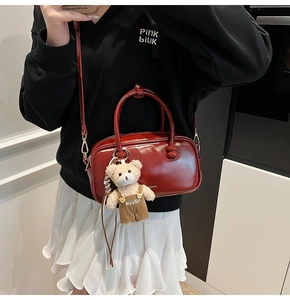 Detail of red glossy leather Boston bag with cute teddy bear charm and adjustable strap