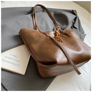 Detail of dark brown tote bag leather texture with ethnic beaded tassel and strap
