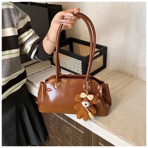 Detail of vintage oil wax leather handbag featuring debossed logo and bear charm
