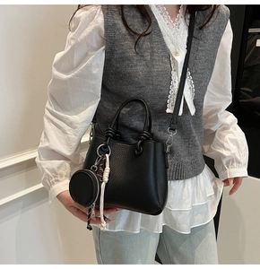 Dettaglio borsa nera in pelle martellata con tracolla rimovibile e mini borsa rotonda
