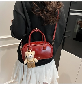Glossy burgundy Boston bag detail with white logo and cute teddy bear pendant charm
