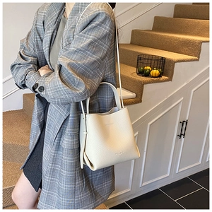 Détail d'un sac seau crème en cuir grainé avec logo doré et finitions soignées