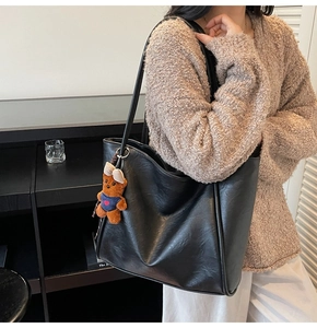 Detailed view of black retro tote bag with brown bear charm on a shoulder strap