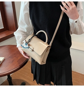Détail du sac cabas crème avec poignée ronde et breloque cheval à bascule bleu