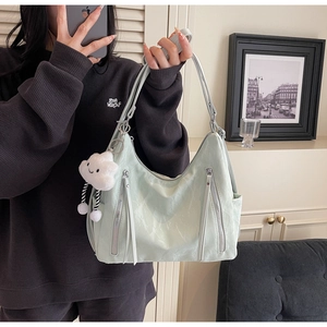 Detail of mint green tote bag with vertical zippers and a white plush cloud charm