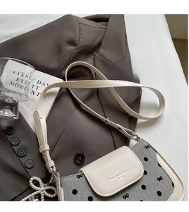 Detailed view of beige leather trim and dot pattern fabric on a crossbody bag