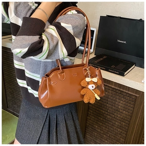 Detail of vintage brown leather handbag with teddy bear charm and embossed logo lettering