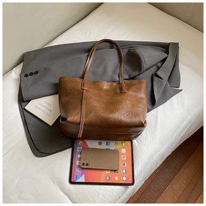 Brown tote bag on white sheets with a tablet to show the spacious large capacity