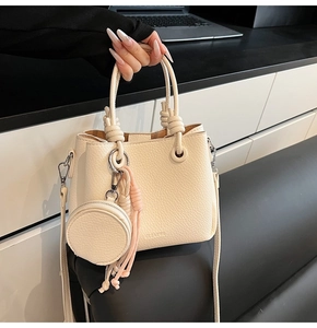 Dettaglio borsa a secchiello in pelle crema con finiture argentate e mini portamonete