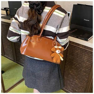 Detail of vintage oil wax leather handbag in brown with a cute teddy bear charm
