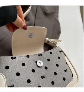 Detail of silver magnetic buckle on grey polka dot fabric handbag with bow pattern