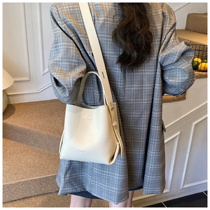 Détail du sac seau beige texture litchi avec logo minimaliste et large bandoulière