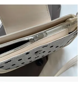 Detail of silver smooth zipper and magnetic closure on a polka dot underarm bag