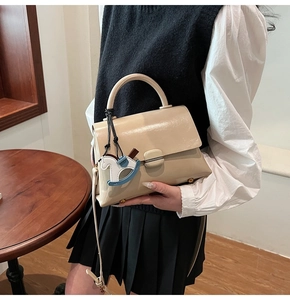 Détail du sac à main beige brillant avec pendentif cheval et bandoulière