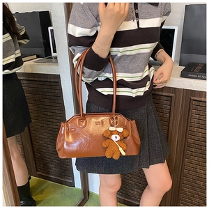 Detail of vintage oil wax leather brown handbag with teddy bear charm and logo embossing