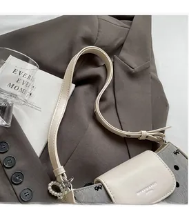 Detail of grey textured fabric and cream leather shoulder bag with pearl charm
