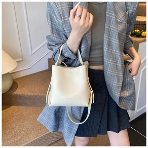 Détail d'un sac seau blanc avec texture en cuir grainé et une bandoulière ajustable