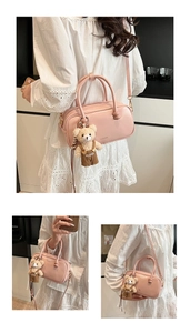 Detailed view of pink Boston bag with a bear charm and clear brand logo on front