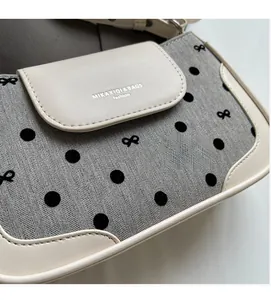 Detail of grey herringbone fabric with black flocking polka dots and bow patterns