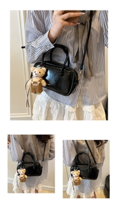 Detail of black patent leather crossbody bag with a cute plush bear charm accessory