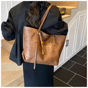 Detail of vintage brown leather tote bag with wooden bead tassel and textured finish