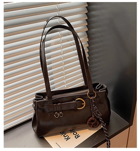 Detail of dark brown leather shoulder bag with gold buckle and knotted accessory