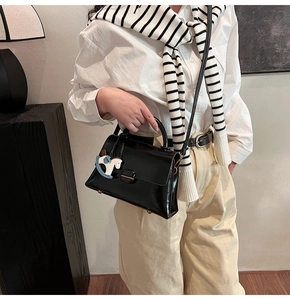 Détail du sac cabas en cuir noir avec clous dorés et breloque en forme de petit poney