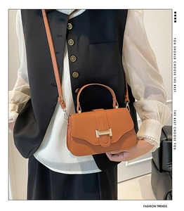Detail of brown textured leather crossbody bag with elegant gold metal twist lock closure