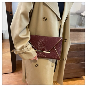 Close-up of burgundy snakeskin envelope clutch with gold metal bar and V-shaped flap