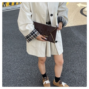 Detail of a brown snakeskin pattern envelope clutch with sleek gold metal edge trim