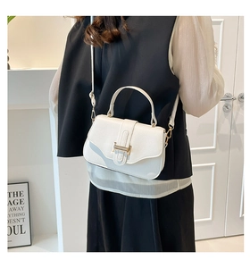 Detail of white lychee leather texture and golden H-shaped buckle on a square bag