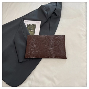 Macro shot of dark brown snake texture on rectangular clutch bag with minimalist style