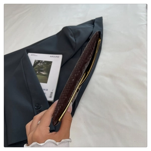 Detail of dark brown snake pattern handbag with gold metal frame closure and slim profile