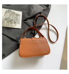 Detail of brown pebbled leather texture and gold metal clasp on a retro square bag