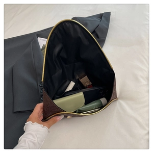 Detail of dark brown ostrich texture clutch showing interior space for phone and makeup
